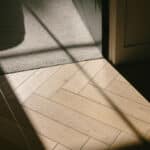 Light coloured wood herringbone floorboards in strong morning sunlight